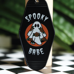 Vintage hotel keychain with a spooky ghost and flowers, adding a touch of spooky charm to your keys or bag.