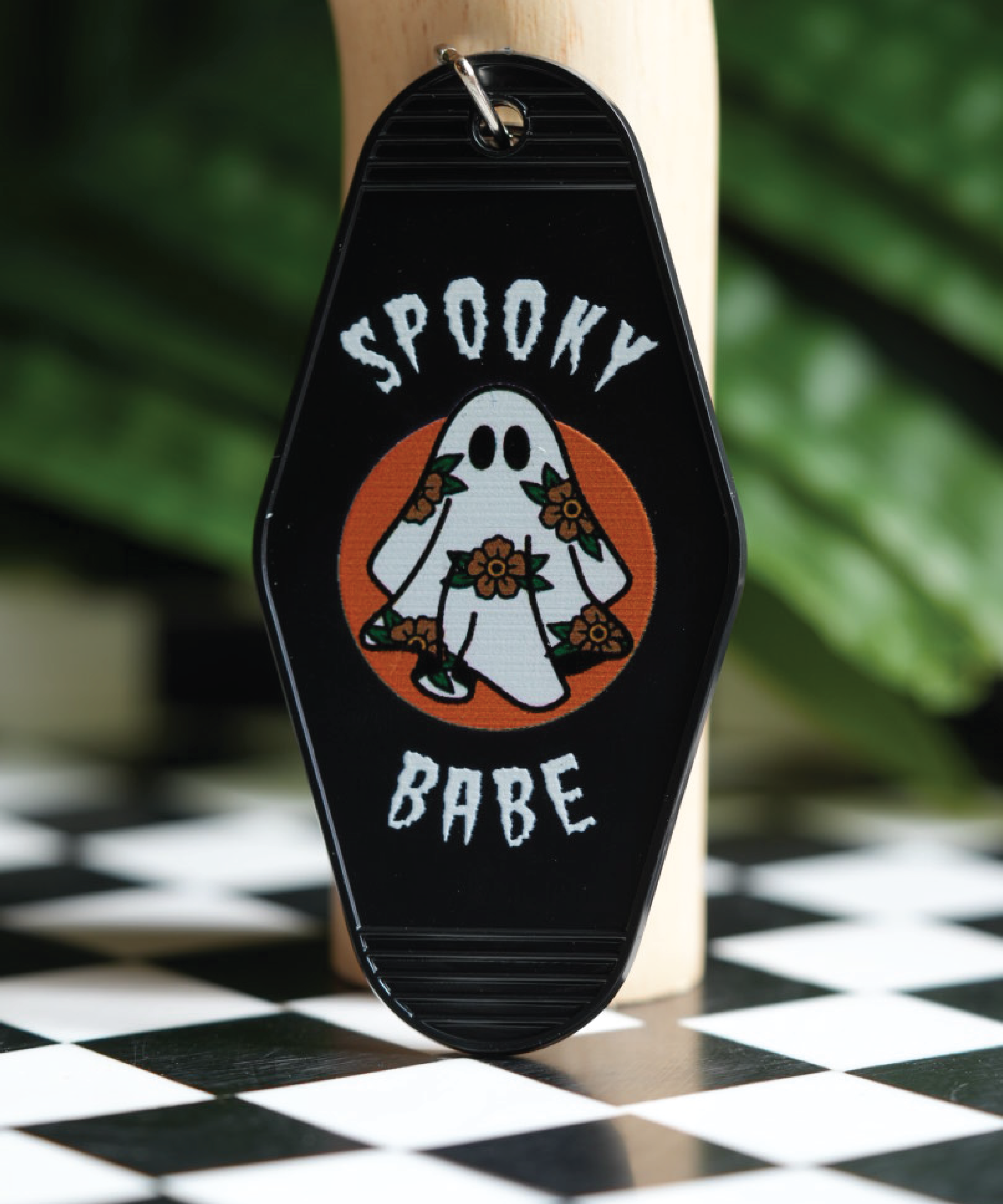 Vintage hotel keychain with a spooky ghost and flowers, adding a touch of spooky charm to your keys or bag.