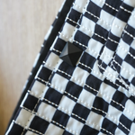 Close-up of the Moxxie Pet Sling Carrier's stylish black and white checkered design, featuring a punk button for added flair!