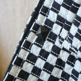 Close-up of the Moxxie Pet Sling Carrier's stylish black and white checkered design, featuring a punk button for added flair!