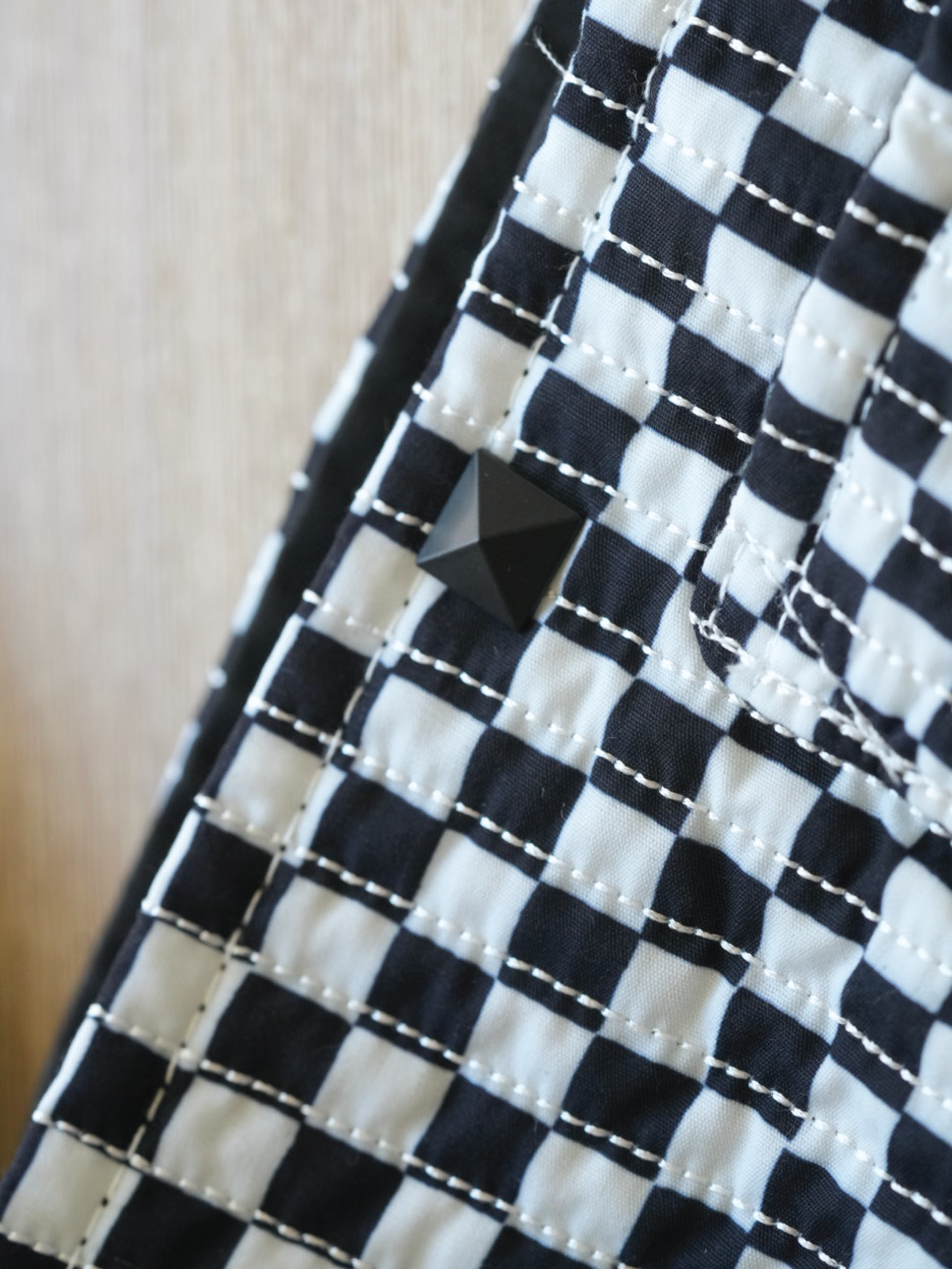 Close-up of the Moxxie Pet Sling Carrier's stylish black and white checkered design, featuring a punk button for added flair!