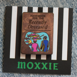 A spooky Beetlejuice-inspired enamel pin featuring the iconic Handbook for the Recently Deceased, perfect for any horror fan.