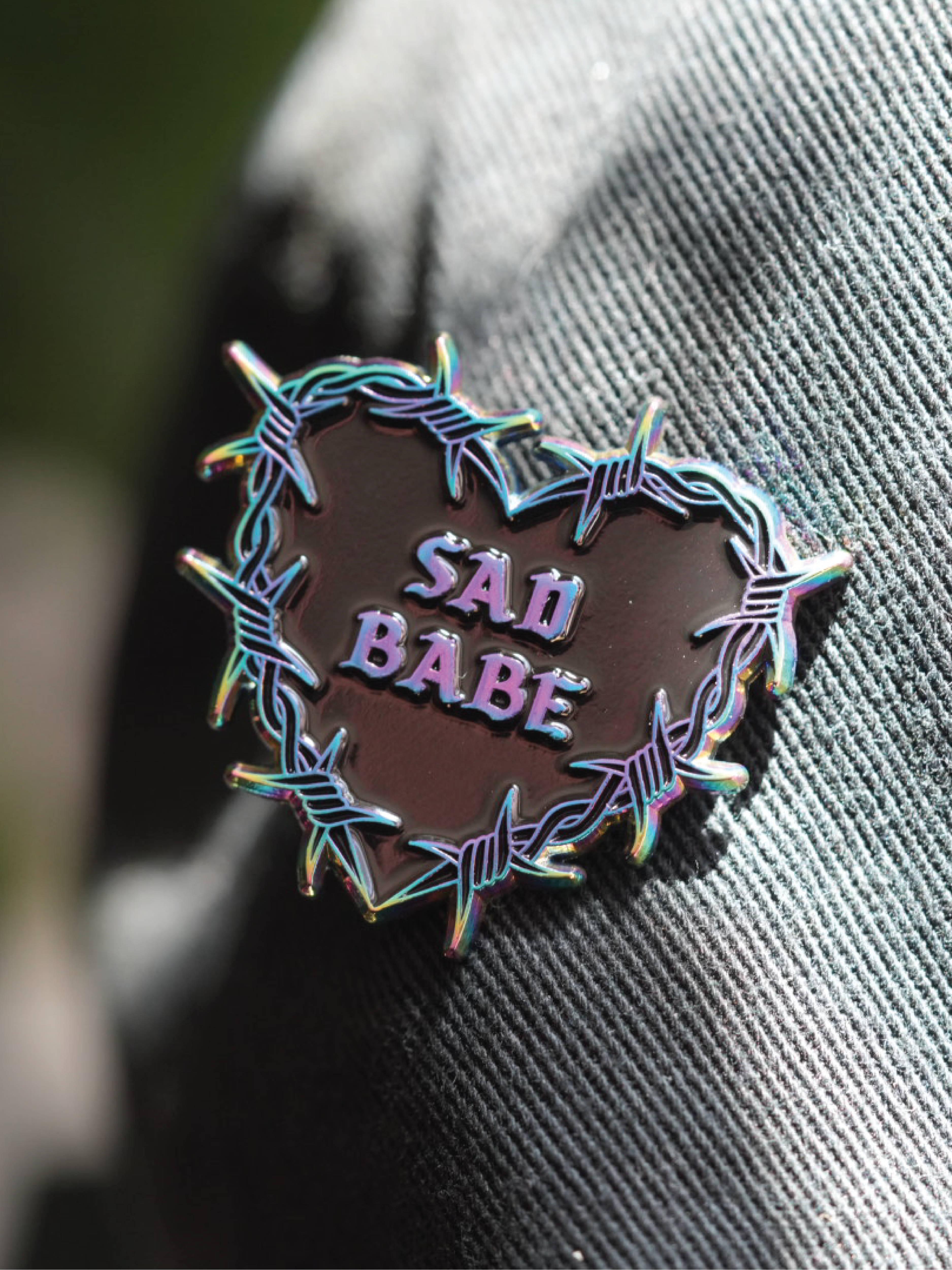 Perfect addition to any emo pin collection, this Sad Babe pin showcases a rainbow metal barbed wire heart and traditional tattoo style.