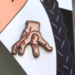 This Wednesday Addams pin set adds a touch of horror to your Halloween look, perfect for any spooky babe. Close up image of the "Thing".