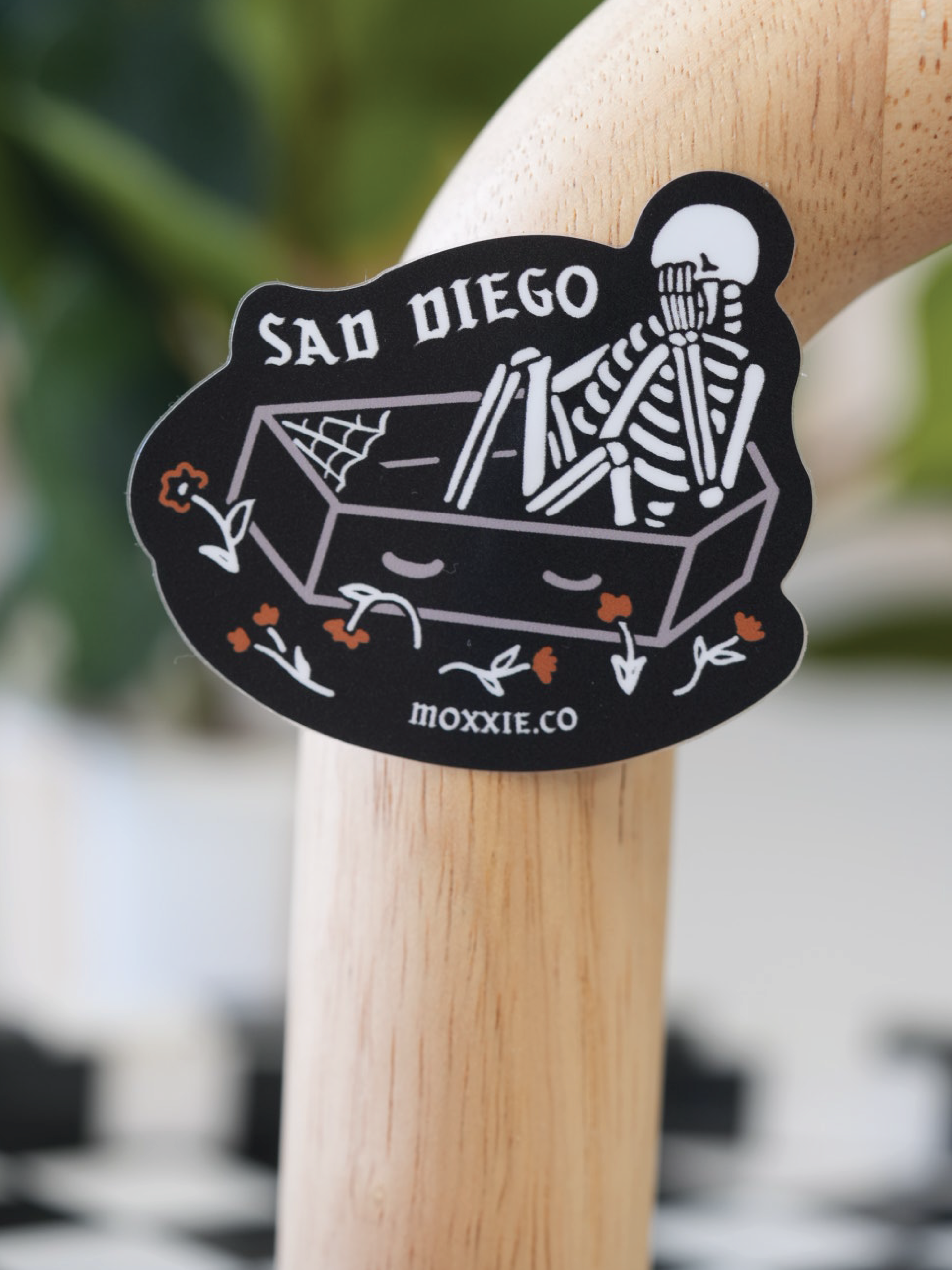 Black 'Sad Diego Gothic' sticker featuring a white skeleton in a coffin, evoking a dark, gothic aesthetic.