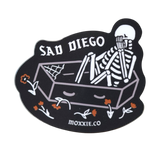 Emo-inspired 'Sad Diego Coffin Sticker' featuring a white skeleton in a coffin, perfect for sad boys, sad girls, and fans of emo nights with its dark, gothic vibe.