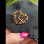 Check out this Sad Babe pin, featuring a barbed copper wire heart and traditional tattoo design, perfect for adding an emo, sad girl vibe to your collection.