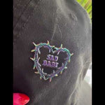 Watch as this Sad Babe pin with a rainbow metal barbed wire heart adds an emo, sad girl touch to your collection, showcasing a traditional tattoo-inspired design.