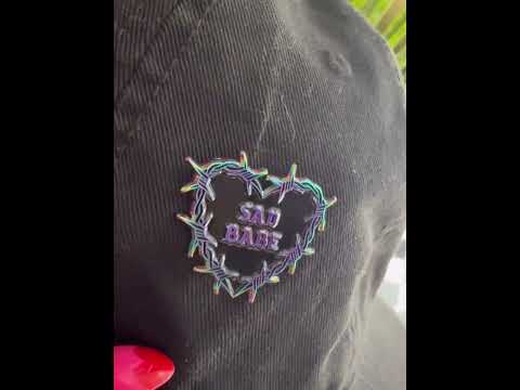 Watch as this Sad Babe pin with a rainbow metal barbed wire heart adds an emo, sad girl touch to your collection, showcasing a traditional tattoo-inspired design.