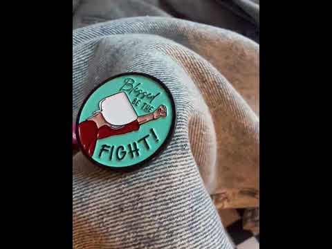 Close-up of the 'Blessed Be the Fight' enamel pin on a denim jacket, symbolizing equality and women's rights in a bold, feminist style.